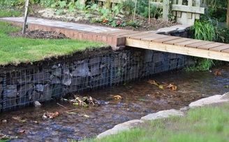 Garden project reclaiming lawn with gabions and elegantly retaining small river